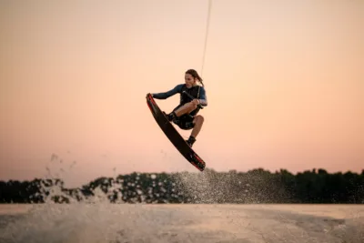 active strong man making trick in jump time with wakeboard on sky background.