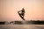 active strong man making trick in jump time with wakeboard on sky background.