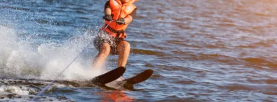 Woman riding water skis closeup. Body parts without a face. Athlete water skiing and having fun. Living a healthy lifestyle and staying active. Water sports theme. Summer by the sea. Banner for website